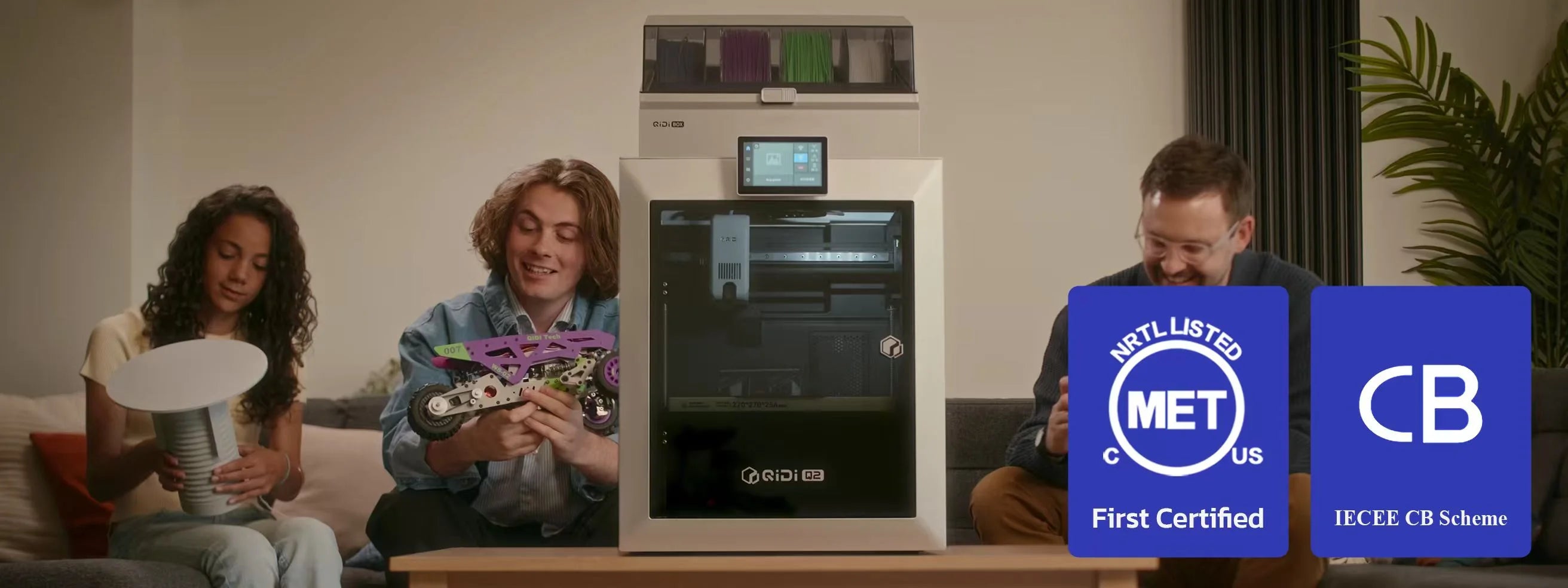 Three people sitting around a 3D printer with certification logos displayed.