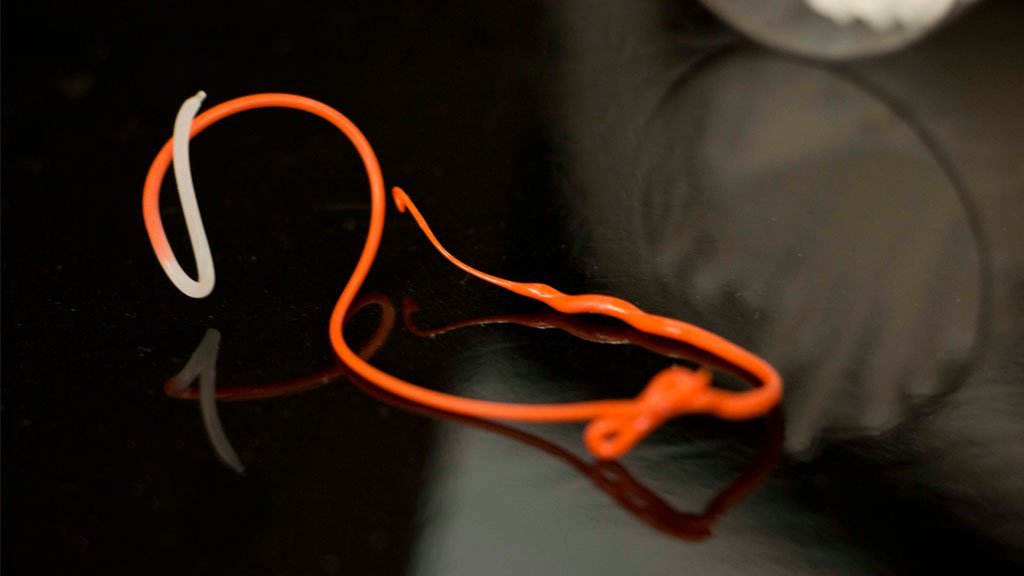 Orange and white fishing hook on a dark surface