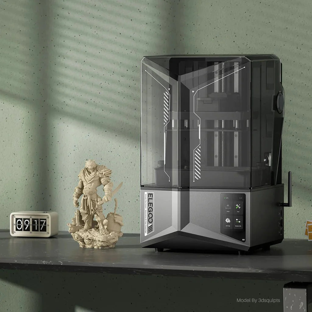 3D printer on a table with decorative items against a green wall