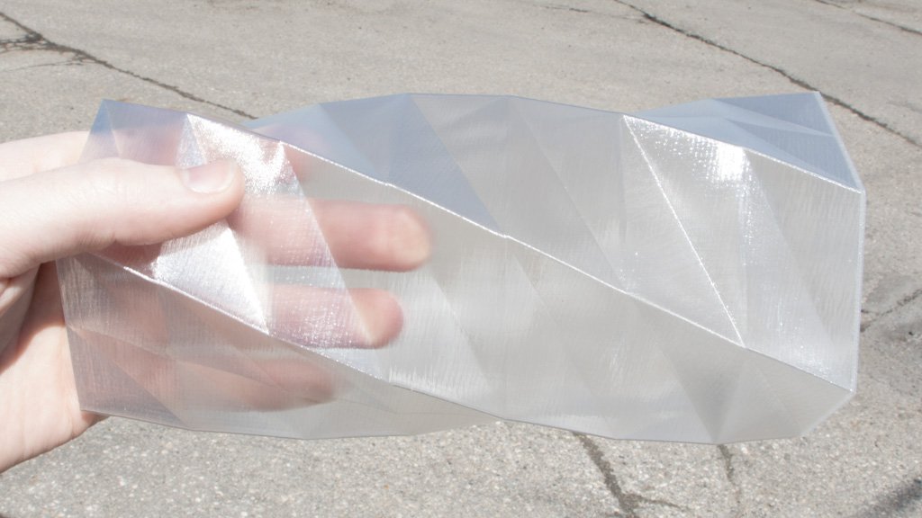 Clear plastic sheet held by a hand on a concrete surface