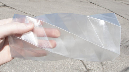 Clear plastic sheet held by a hand on a concrete surface