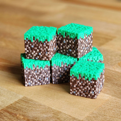 Stack of pixelated green and brown blocks on a wooden surface