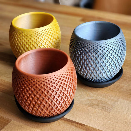 Three textured ceramic pots in yellow, orange, and blue on a wooden surface.