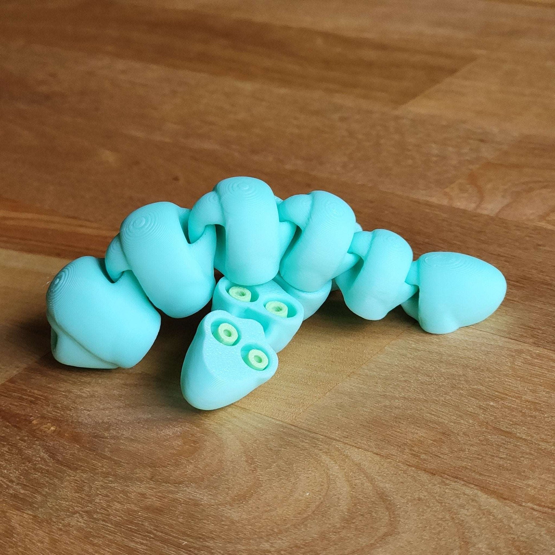 Turquoise silicone caterpillar toy on a wooden surface